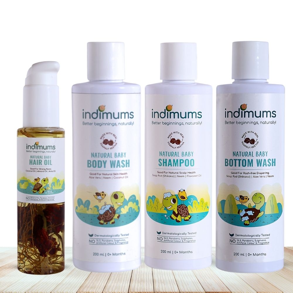 Three bottles of Indimums natural Baby Shampoo, Body Wash , Bottom Wash and baby hair oil on a wooden surface with a white background