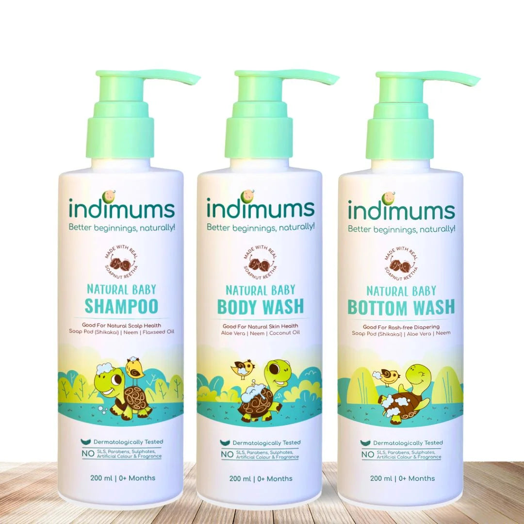 Three bottles of Indimums natural Baby Shampoo, Body Wash & Bottom Wash on a wooden surface with a white background