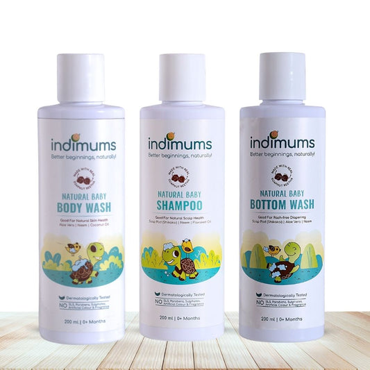 Three bottles of Indimums natural Baby Shampoo, Body Wash & Bottom Wash on a wooden surface with a white background
