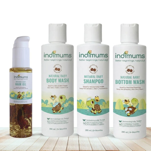 Three bottles of Indimums natural Baby Shampoo, Body Wash , Bottom Wash and baby hair oil on a wooden surface with a white background
