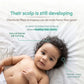 A baby lying on a white blanket with informational text about scalp development and hair care. The text reads, 'Their scalp is still developing' and 'Chemicals filled shampoos can do more harm than good!' with callouts pointing to the baby's curly hair. Indimums baby and kids shampoo