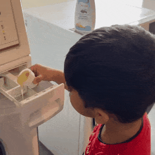 A child pouring the indi mums Natural Baby Laundry Detergent into the washing machine 