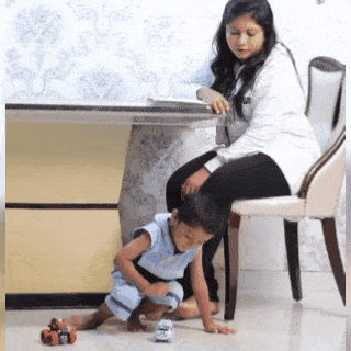 Child playing on the floor while the mother is supervising the little one. 
